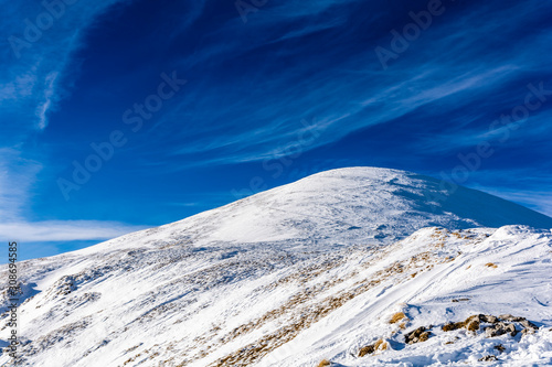 Fototapeta Naklejka Na Ścianę i Meble -  Typical winter mountain landscape. Domed peak covered with white snow and the blue sky.