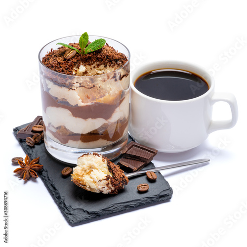 Classic tiramisu dessert in a glass cup and pieces of chocolate on stone cutting board on white background with clipping path