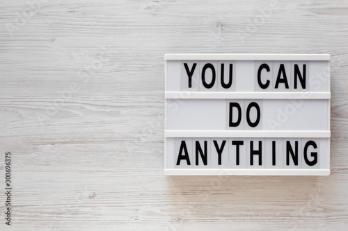 'You can do anything' words on a lightbox on a white wooden surface, top view. Overhead, from above, flat lay. Copy space.