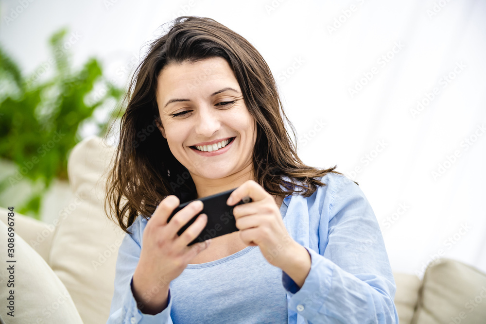 Attractive brunette woman is involved in phone game. She is smiling and trying to pass the level. Copy space. Close up. Attractive brunette woman is involved in phone game. She is smiling and trying to pass the level. Copy space. Close up.