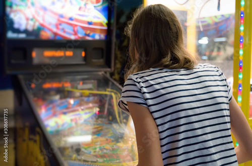 Little girl playing pinball game in theme park. photo