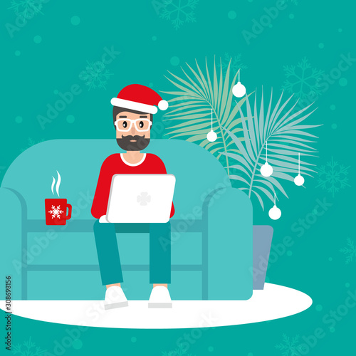happy freelancer man with santa hat on sofa with laptop. creative hipster work at home.
