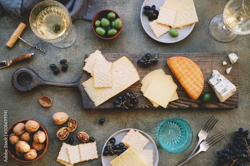 Flat lay of cheese platter with cheese assortment, grapes and nuts. Party or gathering eating concept