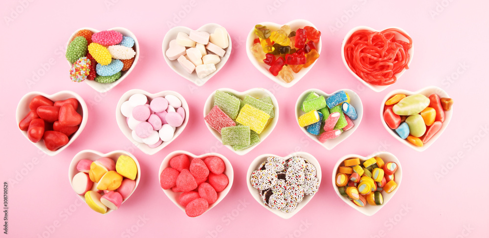 candies with jelly and sugar. colorful array of different childs sweets and treats on pink background