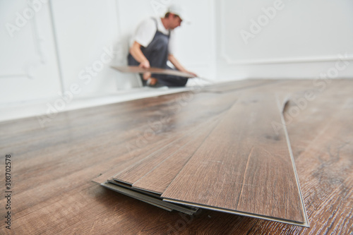 worker laying vinyl floor covering at home renovation photo