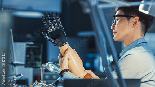 Futuristic Prosthetic Robot Arm Being Tested by a Professional Japanese Development Engineer in a High Tech Research Laboratory with Modern Computer Equipment.