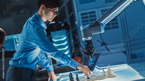 Professional Japanese Development Engineer is Testing an Artificial Intelligence Interface by Playing Chess with a Futuristic Robotic Arm. They are in a High Tech Modern Research Laboratory.