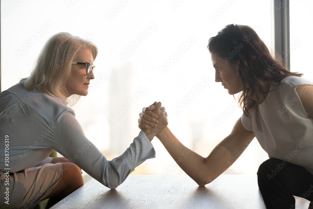 Foto Stock Side view mature and young businesswomen arm wrestling,  confrontation | Adobe Stock