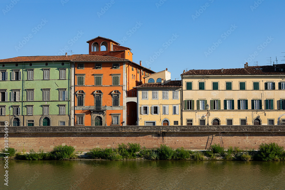 Colorful Historical buildings by Arno river. Row of traditional houses with shutters in Pisa, Italy. Summer day in Tuscany. Old city