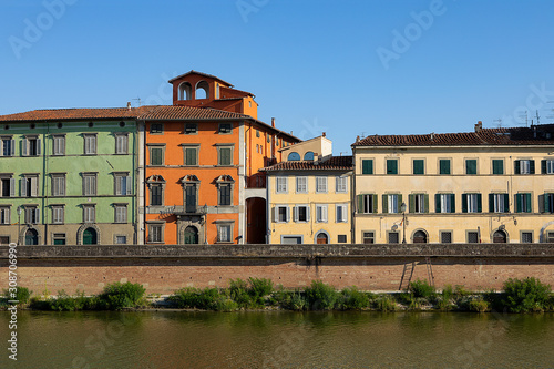 Colorful Historical buildings by Arno river. Row of traditional houses with shutters in Pisa  Italy. Summer day in Tuscany. Old city
