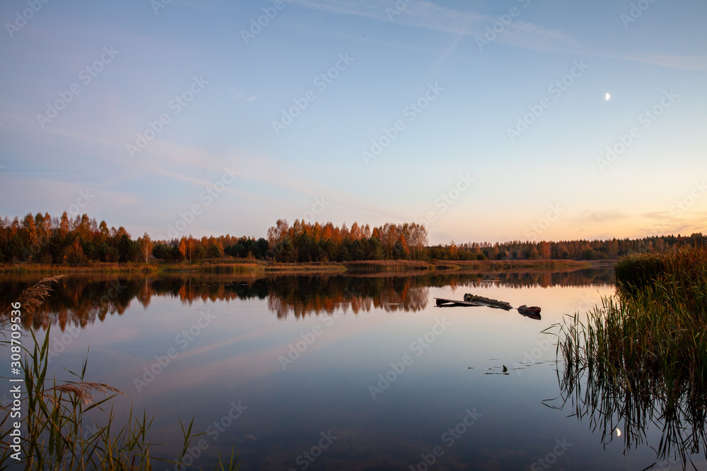 Ozierany Lake during evening. Small moon reflected in the water on the right side of the picture. Ozierany Lake during evening. Small moon reflected in the water on the right side of the picture.