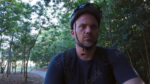 man riding a bike on a footpath in slow motion close up on face. photo