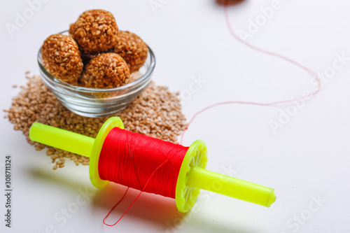 Til Gul OR Sweet Sesame Laddu in glass bowl with Fikri for Indian festival Makar Sankranti over white background  photo