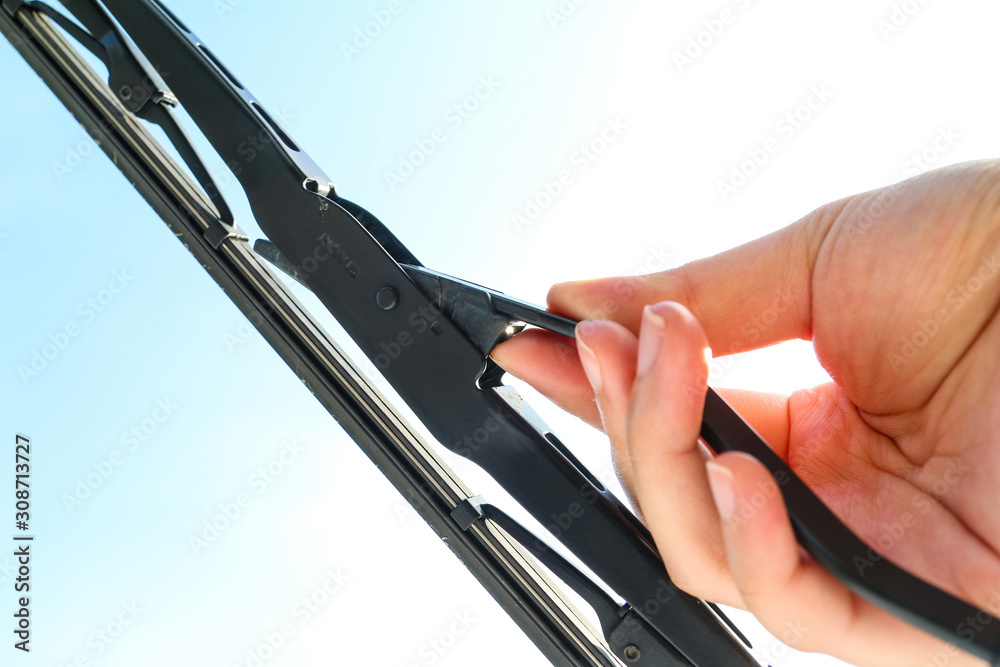 Hand holding a car's side lock windshield wiper. Changing vehicle's wiper