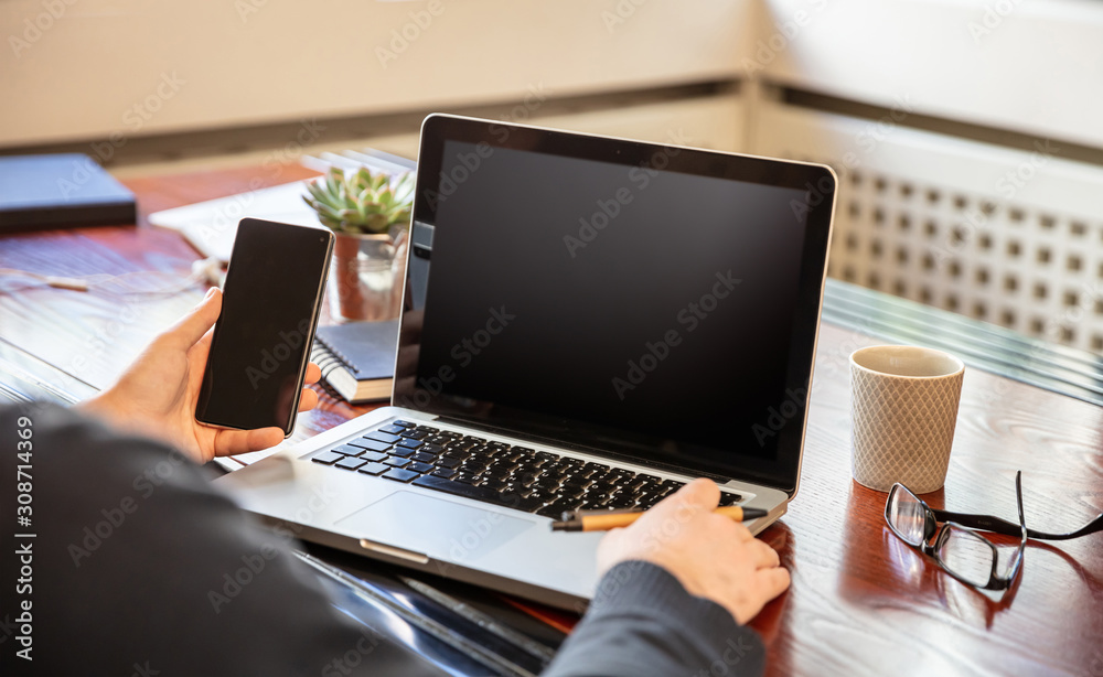 Laptop and smartphone with black blank screens, office interior background Laptop and smartphone with black blank screens, office interior background