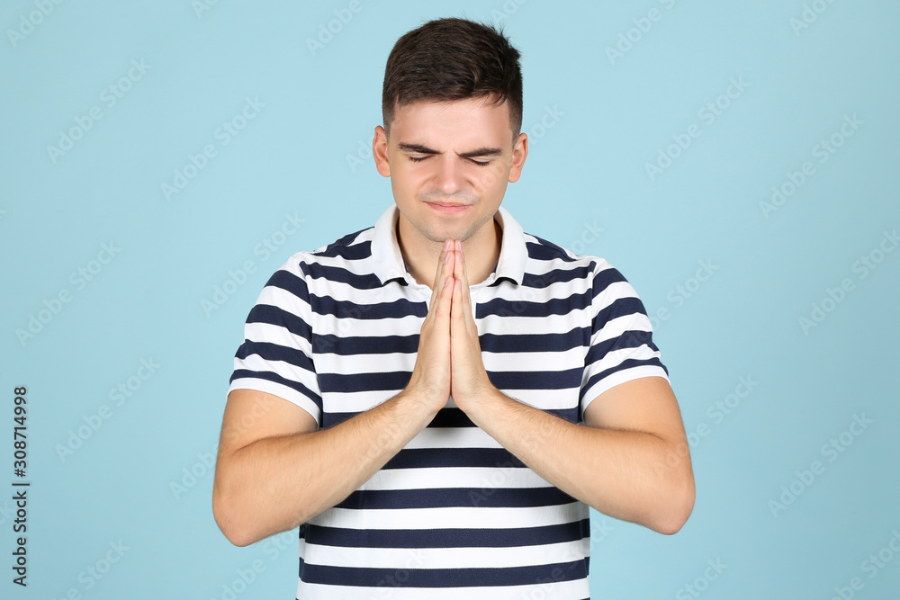 Young praying man on blue background Young praying man on blue background
