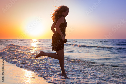 Attractive Girl Jumping on the Beach Having Fun, Summer vacation holiday Lifestyle. Happy women jumping freedom on white sand.Happy Carefree Woman in the blue dress Enjoying Beautiful Sunset.