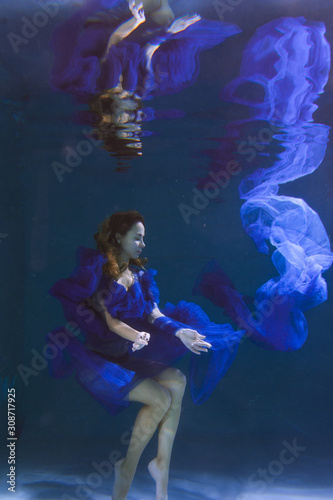 Beautiful girl in a blue dress swims underwater in the pool or in the sea. © Underwater girls