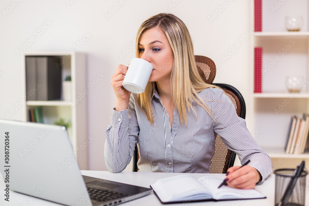 Businesswoman drinking coffee while working in her office. Businesswoman drinking coffee while working in her office.