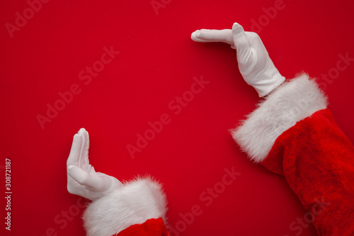 Santa Claus making frame with hand on red background with copy space photo