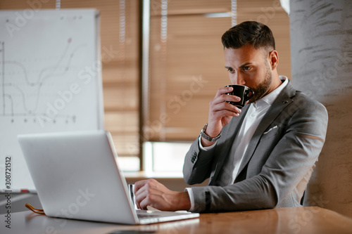 Portrait of handsome businessman working in office and drinking coffee.