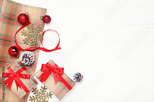 Gift boxes with ornaments and cones on white wooden table