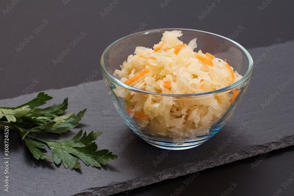 Fermented cabbage with herbs and spices in glass bowl on the black background Fermented cabbage with herbs and spices in glass bowl on the black background