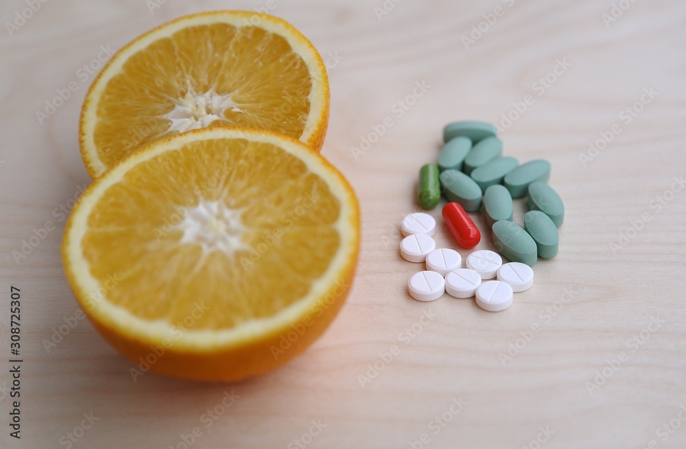 Fototapeta premium Choice between healthy lifestyle and lecture, choice between vitamin in orange or pills