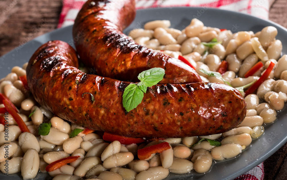 Beans with grilled sausages on wooden background Beans with grilled sausages on wooden background