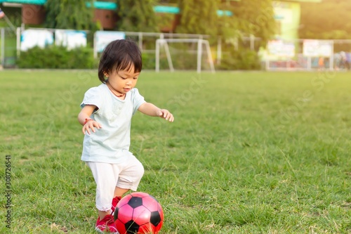 Canvas Print Happy Asian baby child girl playing and​ kicking a​ ball toys at the field playground