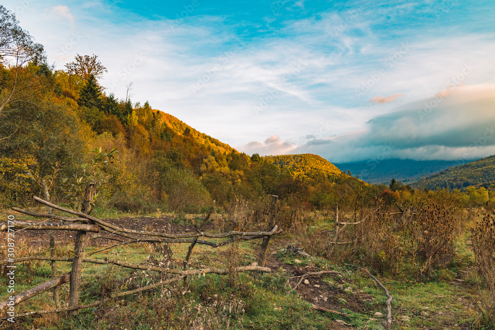 colorful moody autumn time golden season rural highland village outskirts scenic view with wooden broken fence and mountain picturesque landscape background 