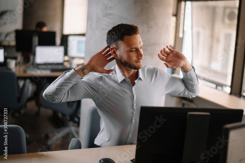 Handsome businessman in office. Businessman stretching his hands. 