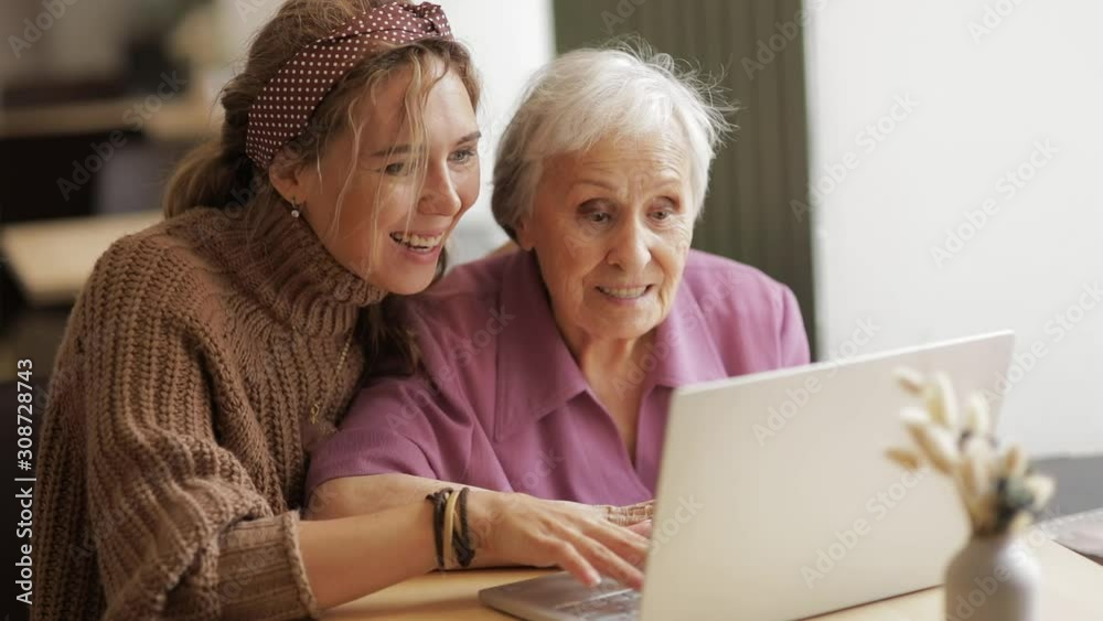 granddaughter gives gift of a laptop and shows how to use a very old grandmother birthday. the concept of family, generations, love for relatives. girl and grandmother look at the laptop granddaughter gives gift of a laptop and shows how to use a very old grandmother birthday. the concept of family, generations, love for relatives. girl and grandmother look at the laptop