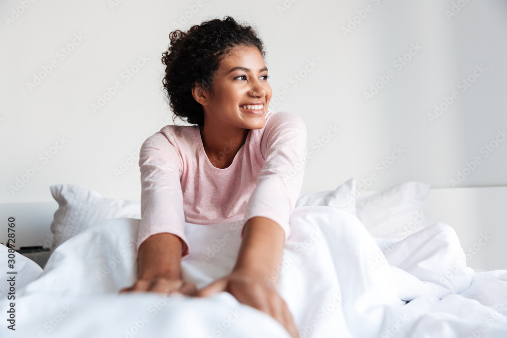 Smiling beautiful young african woman sitting in bed Smiling beautiful young african woman sitting in bed
