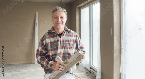 Friendly plasterer in the interior of newly constructed house photo