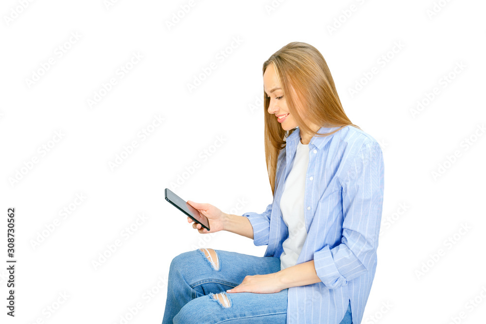Young woman sitting and writing message on smartphone over withe background, isolated. Young woman sitting and writing message on smartphone over withe background, isolated.