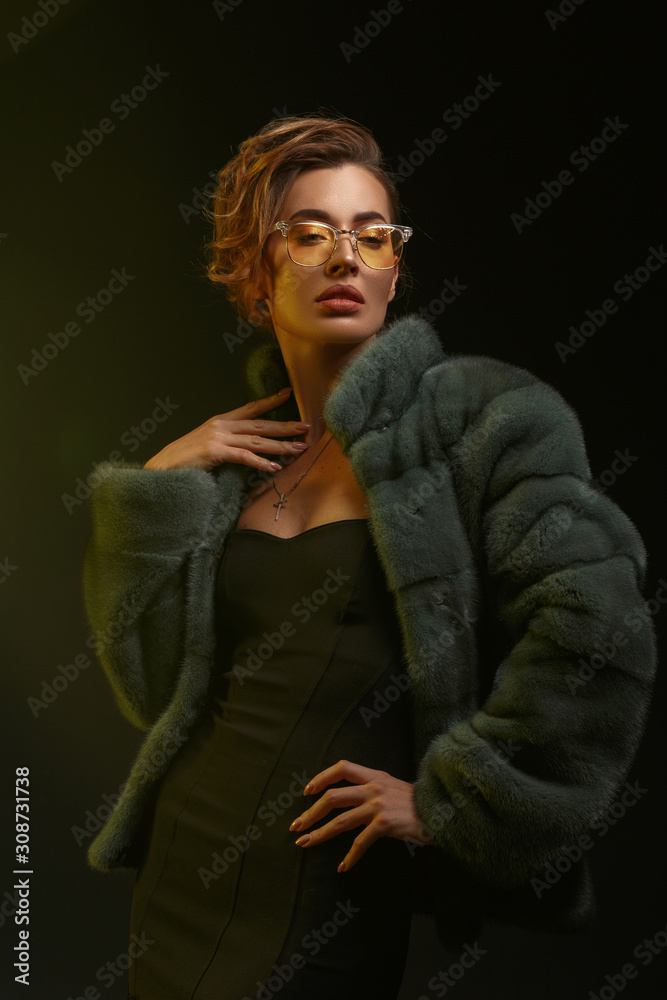 Portrait of a spectacular girl in yellow glasses jewelry and a fur coat made of natural fur. Portrait of a spectacular girl in yellow glasses jewelry and a fur coat made of natural fur.