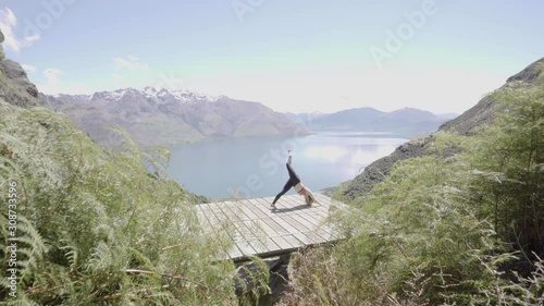 Girl performing yoga on summer day overlooking blue lakes and mountain ranges in Queenstown New Zealand. photo