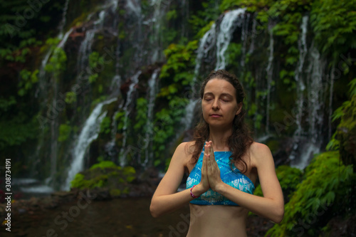 Close up of namaste mudra. Young woman meditating  practicing yoga and pranayama with gyan mudra near waterfall. Banyu Wana Amertha waterfall Wanagiri  Bali.