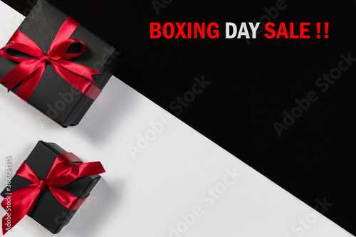 Boxing day sale online shopping.,Top view of black christmas gift boxes with red ribbon and text on black and white background with copy space for text. © pongsakrit