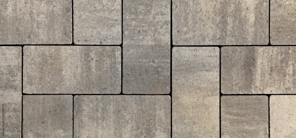 Fototapeta premium Regular shape blocks, texture, background. Paving slabs of gray blocks of flat shape, close-up. New pavement in the city park. Arrangement of a park way