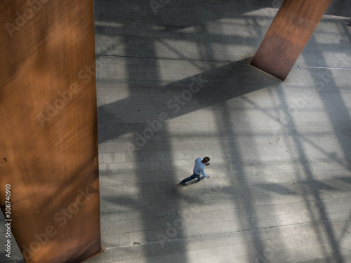 Lonely walker across square with beautiful shadow lines