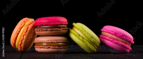 Heap of french colorful macaroons on wooden table isolated on black