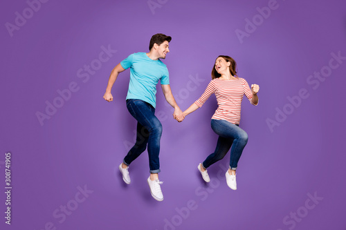 Full body profile photo of crazy funky two people guy lady jumping high rushing season sales black friday wear casual blue striped t-shirts jeans shoes isolated purple color background