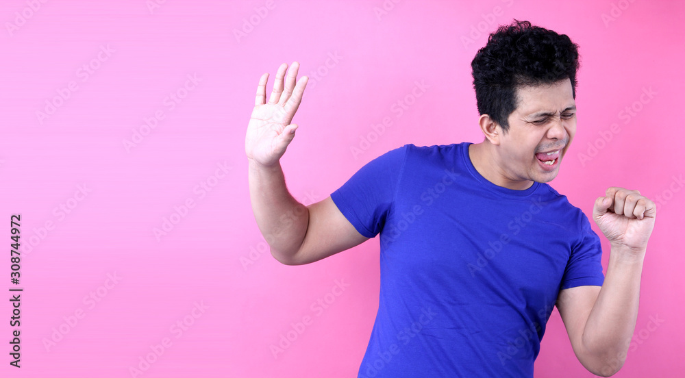 Portrait Handsome Asia man singing loud while standing on pink background in studio With copy space. Portrait Handsome Asia man singing loud while standing on pink background in studio With copy space.