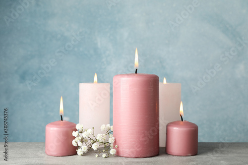 Group of burning candles and flower against blue background, close up