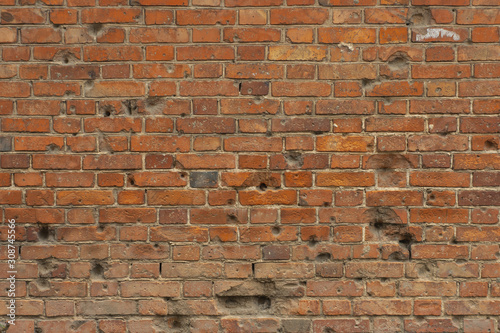 Old red brick wall with bullet holes photo