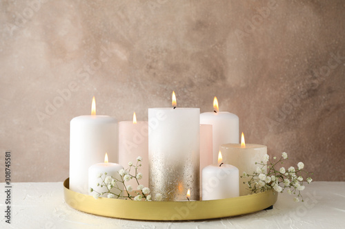Burning candles, tray and flower on white table, space for text