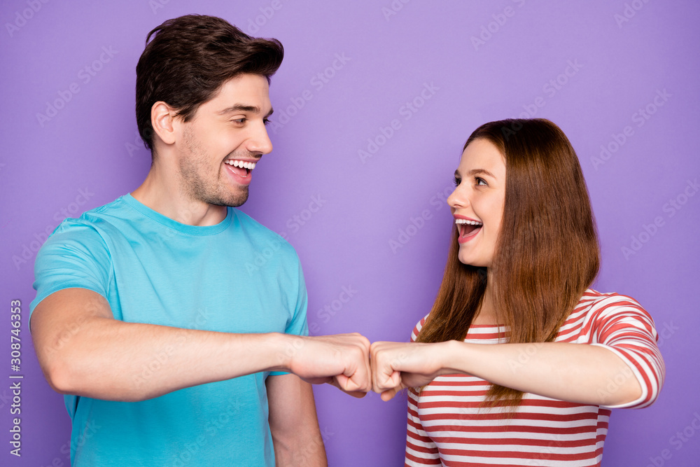 Photo of two funny people couple positive emotions good mood giving fist bump have agreement deal wear stylish casual outfit t-shirts blue striped isolated purple color background Photo of two funny people couple positive emotions good mood giving fist bump have agreement deal wear stylish casual outfit t-shirts blue striped isolated purple color background