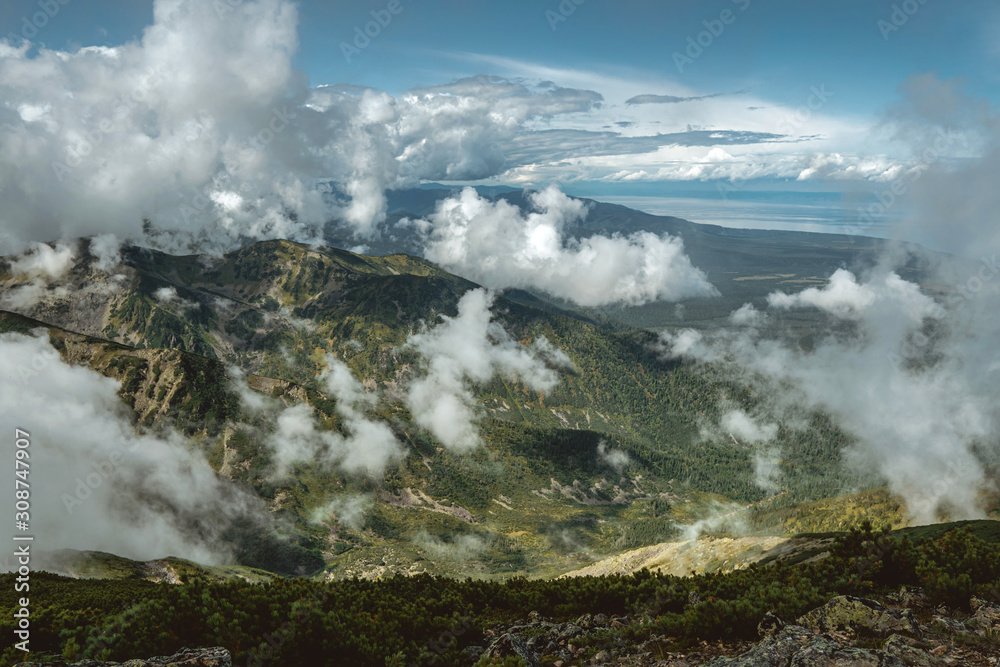 Majestic view of the landscape from the top to the mountains in the clouds on a Sunny day in summer